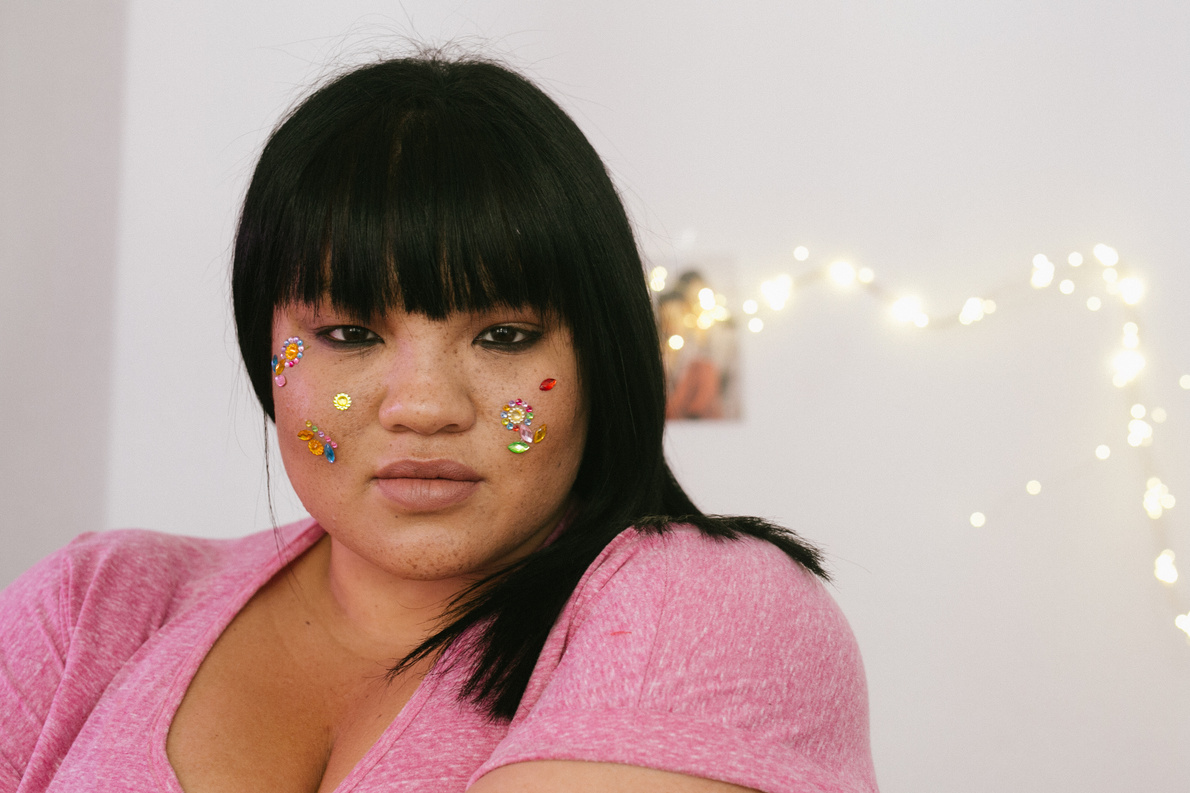 Sensual plus size female with shiny rhinestone on face looking at camera