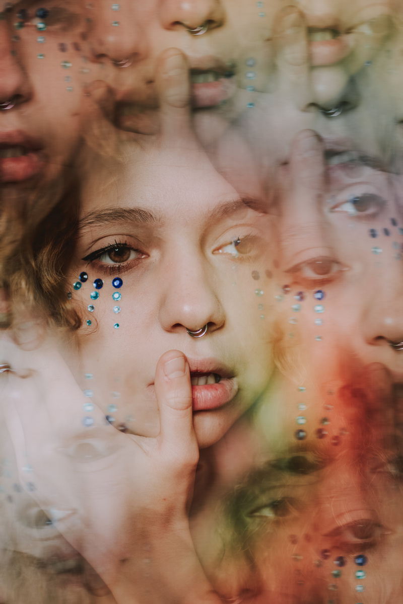 Kaleidoscopic female face with rhinestones on cheeks and nose piercing